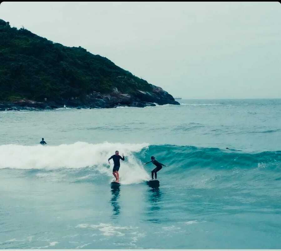 Cláudia Bitencourt dropando uma onda junto com o Bidart